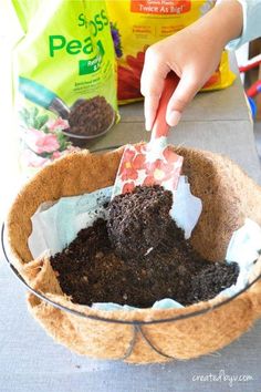 a person scooping dirt into a bowl with a plastic fork and paper bag in the background