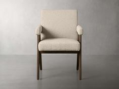 an upholstered chair sits in front of a gray wall, with no one around it