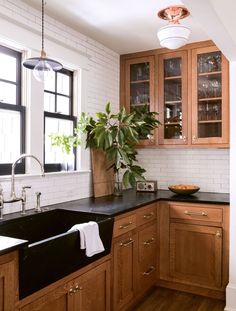 a kitchen with wooden cabinets and black counter tops, along with a white brick wall