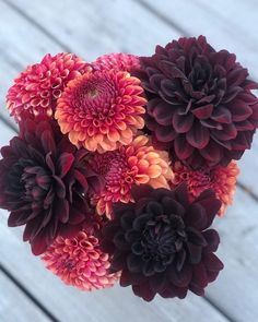 a bouquet of red and orange flowers sitting on top of a wooden table