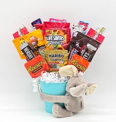 a stuffed animal sitting in a blue bucket filled with snacks and candy bar wrappers