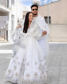 a man and woman dressed in white are walking down the street