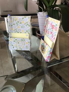 two notebooks sitting on top of a glass table next to a potted plant