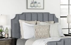 a bed with white pillows and gray headboard