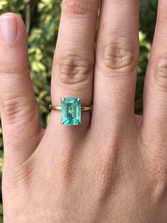 a woman's hand with an emerald ring on it