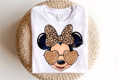 a t - shirt with minnie mouse ears on it sitting next to a wicker basket