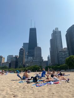 people relaxing on the beach in front of skyscrapers