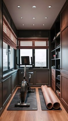 a home gym with exercise equipment and yoga mats on the floor in front of large windows