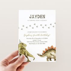 a person holding up a birthday card with an image of a dinosaur