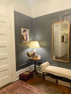 a room with blue walls and a white bench in the corner next to a mirror