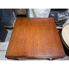 a wooden table sitting on top of a floor next to a chair and other furniture