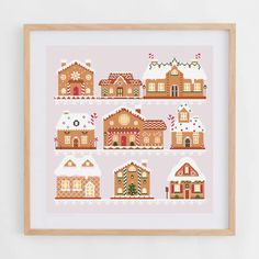 a cross stitch pattern with gingerbread houses on pink and white background, framed in wooden frame