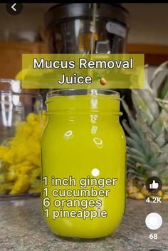 a glass jar filled with liquid sitting on top of a counter next to pineapples