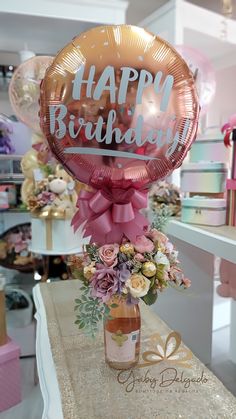 a happy birthday balloon sitting on top of a table next to a vase filled with flowers