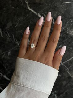 a woman's hand with pink manicured nails and a diamond ring on it