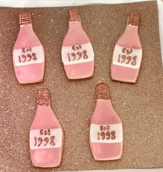 six decorated cookies in the shape of pink bottles with numbers on them are sitting next to each other