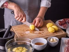 a person cutting up food on top of a wooden cutting board