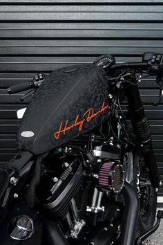 a black motorcycle parked in front of a garage door with an orange harley davidson logo on it