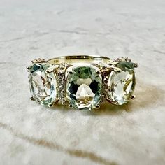 Beautiful 14 karat yellow gold three-stone cocktail ring featuring three natural oval green quartz (green amethyst/prasiolite). The gemstones weigh approximately 3.6 carats, and are accented by 20 diamonds weighing approximately 0.08 CTTW. Size 7 US / N 1/2 - O UK / 54 FR. > Resizing included. This ring can be resized to fit most fingers. Please contact us for details. Resized rings are final sale. Free resizing does not apply to discounted rings over 15% off. Condition: Excellent/New. - 14 day Elegant Green Oval Amethyst Ring, Elegant Oval Three-stone Gemstones, Elegant Three Stone Oval Gemstones, Oval Green Amethyst Ring For Anniversary, Green Oval Amethyst Ring For Anniversary, Green Amethyst Oval Ring For Anniversary, Fine Jewelry Green Amethyst Oval Ring, Luxury Green Amethyst Ring With Accent Stones, Elegant Green Amethyst Topaz Ring