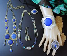 This LOT includes all 6 vintage Afghan jewelry pieces as shown. These pieces are mostly souvenir jewelry - that is jewelry that was made for sale in local souks for sale to travelers as simple trinkets. Not always exquisitely made, but replicas of old tribal jewelry pieces. The Lapis stones on several of them is lapis-composite - which is Lapis-Lazuli that has been pulverized, mixed with resin, and made into reconstituted stone. It is real lapis, just not in its natural state. Includes: ---> 1 Wide Afghan cuff bracelet with large Lapis stone (composite?) and incised band. 7-1/4 inch wrist circumference, including gap. ---> 1 Very-Large oval raised-dome ring with ornate design and lapis stone. Size 12.25 (Very large) ---> 1 Multi-strand Afghan necklace with lapis and adventurine beads. Larg Antique Nickel-free Jewelry For Festivals, Vintage Handmade Festival Jewelry, Bohemian Jewelry With Unique Variations For Collectors, Vintage Jewelry For Jewelry Making And Festivals, Artisan Handmade Jewelry Vintage Collection, Vintage Nickel-free Jewelry For Festivals, Nickel-free Vintage Jewelry For Festivals, Artisan Brass Jewelry For Collectors, Vintage Blue Jewelry With Unique Variations