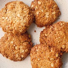 four oatmeal cookies sitting on top of a white plate with some nuts