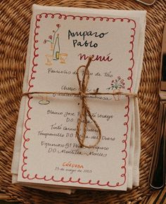 the menu is wrapped in twine and tied up with brown string, sitting on top of a wicker basket next to utensils