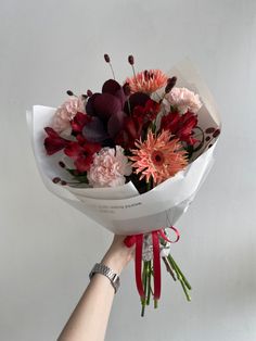 a hand holding a bouquet of flowers on a white background with red and pink colors