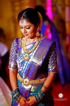 a woman in a blue and gold sari is looking down at her hand on her hip