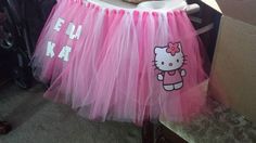 there is a hello kitty cake on top of a table with pink tulle skirt