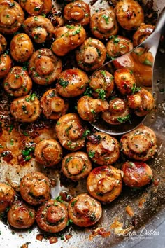 a pan filled with cooked mushrooms covered in sauce and garnished with parsley