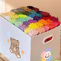 a box filled with lots of different colored cupcakes on top of a wooden floor