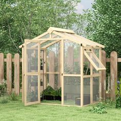 a small wooden greenhouse sitting on top of a lush green field