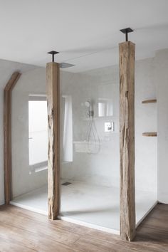 an empty room with two wooden poles in the middle and a shower head mounted to the wall