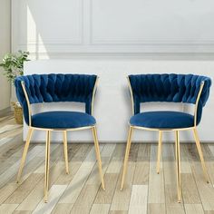 two blue chairs sitting next to each other on top of a hard wood floor in front of a white wall