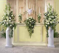 three tall white vases with flowers and greenery