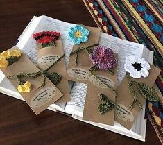 some paper flowers are sitting on top of an open book with tags attached to them