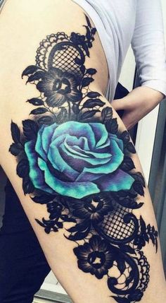 a woman's thigh with a blue rose tattoo on the side and black lace around it