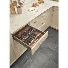 an open drawer in a kitchen with utensils and breadsticks on the counter