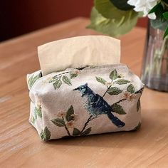 a small pouch sitting on top of a wooden table next to a vase with flowers