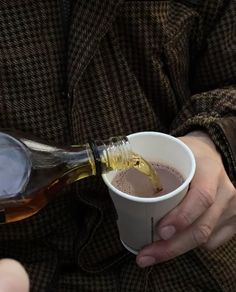 a person pouring some liquid into a cup