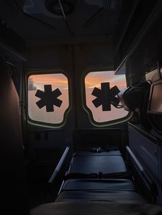 the inside of an ambulance with two large windows at sunset, and one is empty