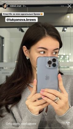 a woman taking a selfie with an iphone in front of her face and holding it up to the camera