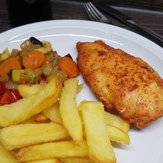 a white plate topped with chicken, fries and vegetables