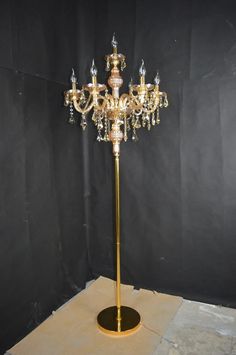 a gold colored chandelier is on display in a room with black walls and flooring