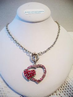 Pink double heart necklace. It measures approx. 19 inches and has a toggle clasp closure. Made with a light pink rhinestone heart silhouette and a smaller solid hot pink rhinestone heart. Silver tone. Perfect for give or wear on Valentine's Day. All sales are final and as is. Thank you for looking. You may also love this: https://www.etsy.com/listing/584789387/heart-silhouette-pendant-necklace?ref=shop_home_active_1 Valentines Day Costume, Pink Heart Pendant, Heart Silhouette, Double Heart Necklace, Carnelian Ring, Rhinestone Heart, Lovely Necklace, Lovely Earrings, Pink Rhinestones