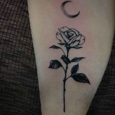 a black and white rose tattoo on the right arm with a crescent moon behind it