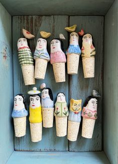 several small wooden dolls are in a blue box with birds on top, and one is holding a bird