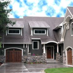 a large gray house with two garages on the front and one car parked in front