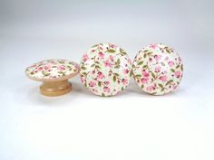 two knobs with pink flowers on them are next to a small wooden standup