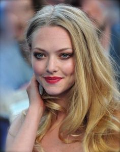 a woman with long blonde hair and blue eyes is posing for the camera while people look on